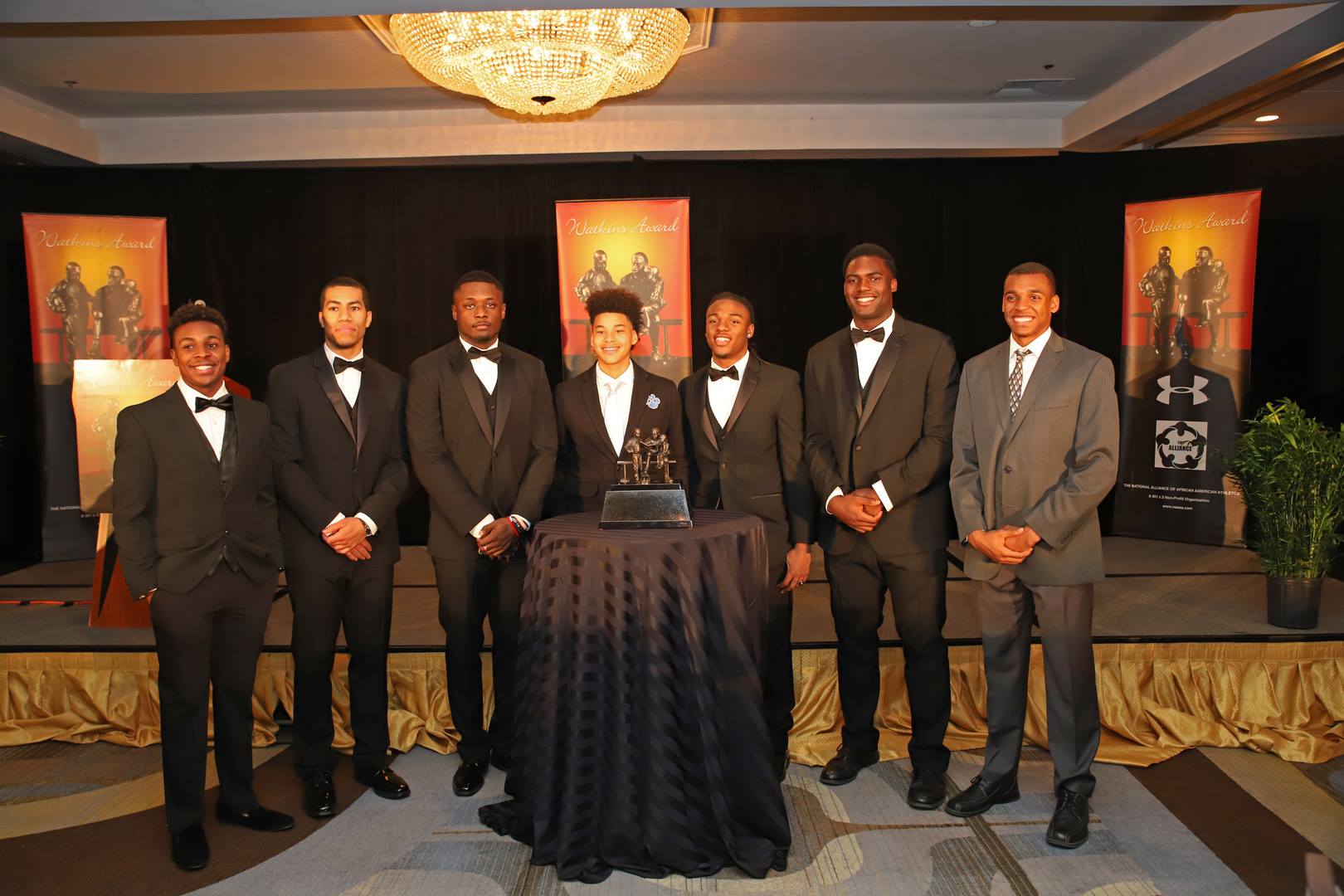 Watkins Award honorees in tuxedos with the Franklin D. Watkins Memorial Trophy at the NAAAA gala